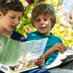 Two boys sitting ina tree reading The Lazy Rabbit and All in the Same Boat hardbacks